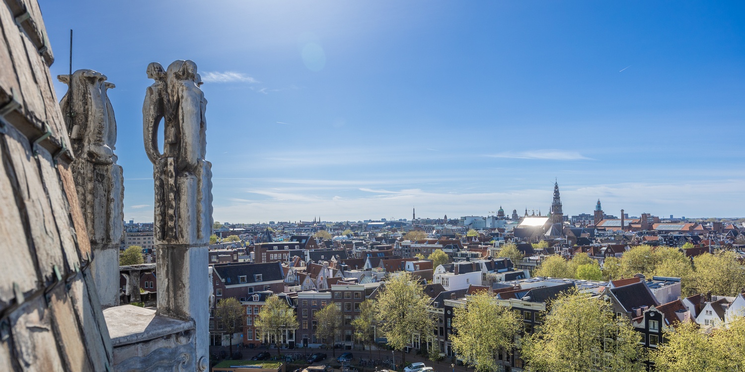 Ruime Junior Suite in Grand Hotel Amrâth Amsterdam met zithoek, hoge ramen en warme art-nouveaustijl.