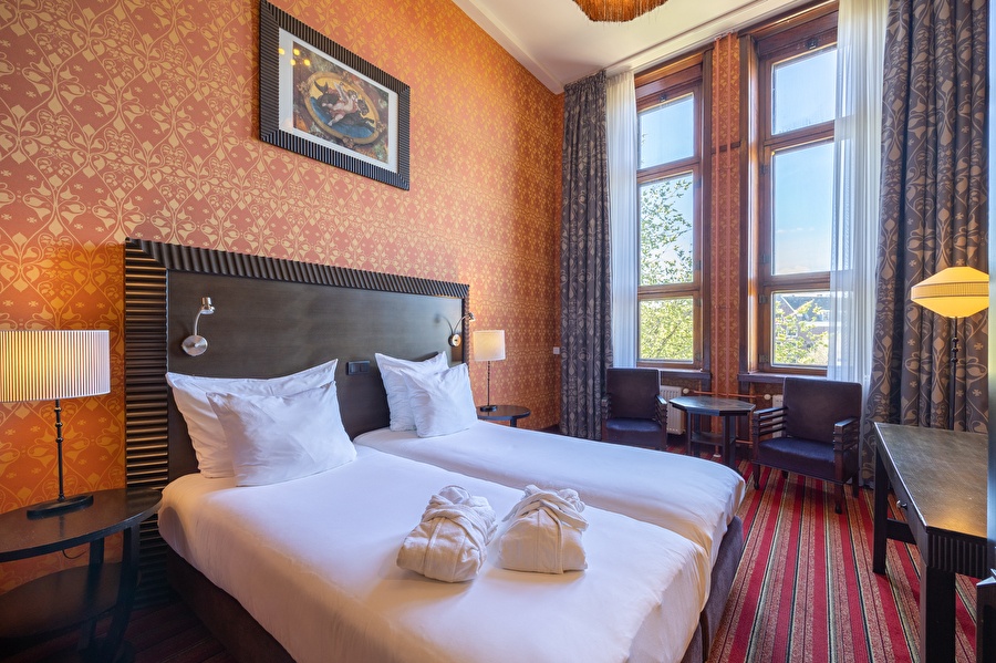 Luxury double room with two single beds, high windows, and a view of the Amsterdam canal.