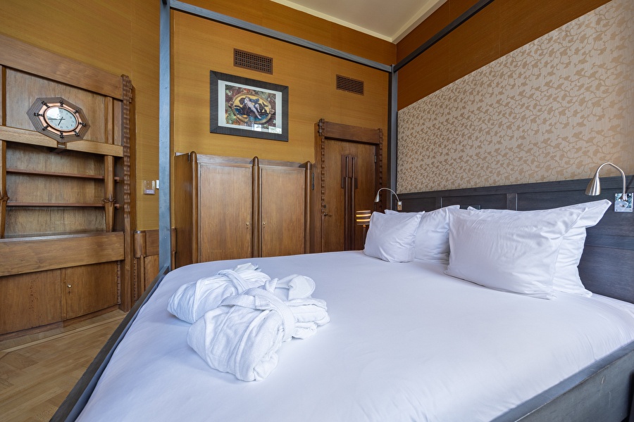 Bedroom of the Executive Suite at Grand Hotel Amrâth Amsterdam with art-deco details, wooden furniture, and king-size bed.