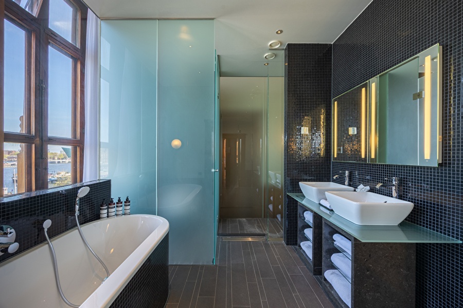 Luxurious bathroom of the Executive Suite with freestanding bath, double sink, and view over the Oosterdok.
