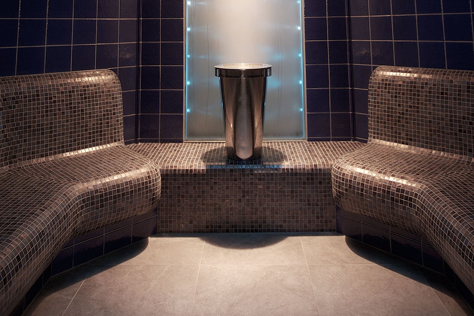 Stoomcabine van de Spa & Wellness in Grand Hotel Amrâth Amsterdam met mozaïekbanken en verlichte waterval.