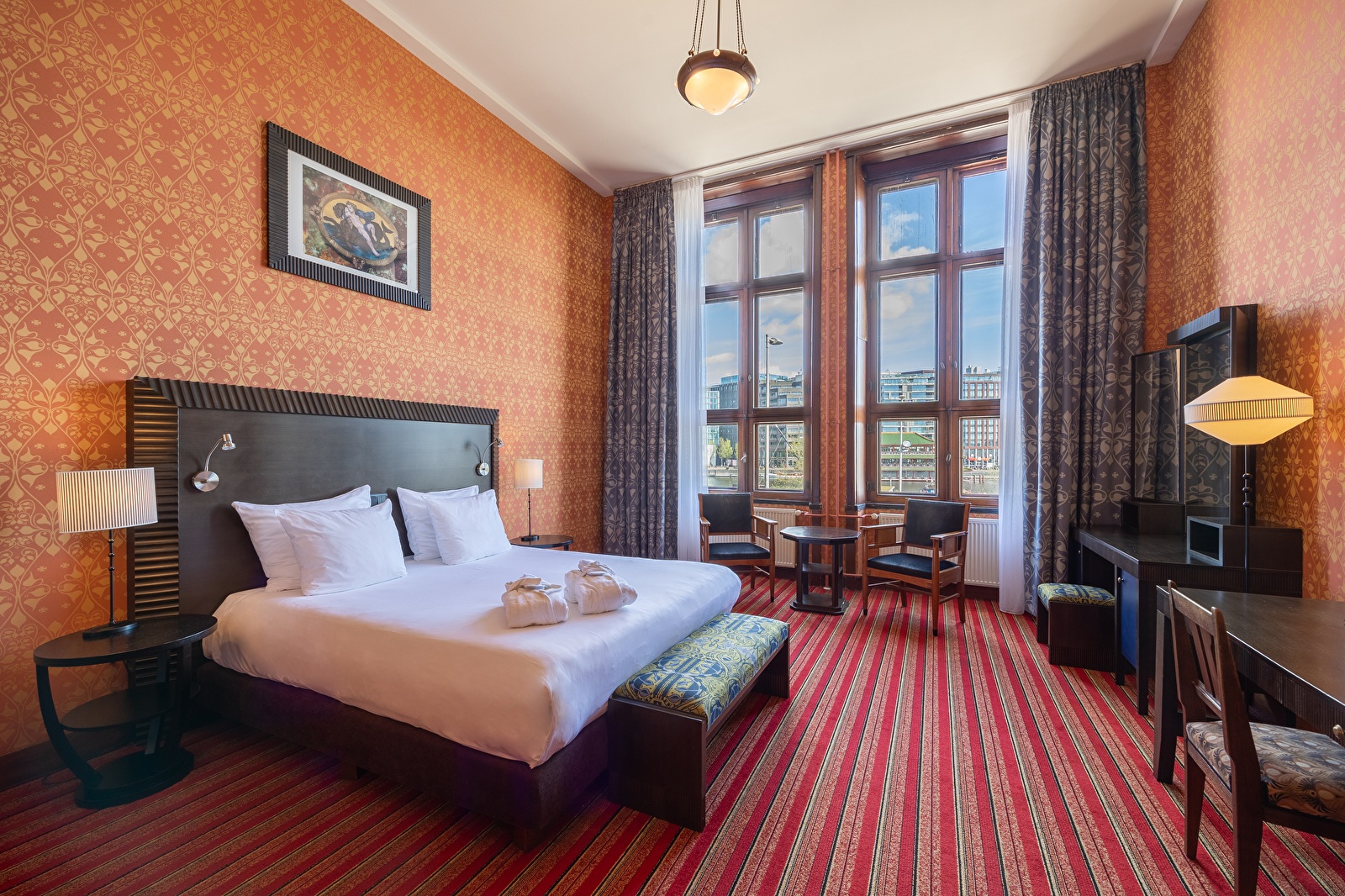 Superior Deluxe kamer in Grand Hotel Amrâth Amsterdam met hoge plafonds, grote ramen met uitzicht op de stad, art-deco interieur en warme kleuren.
