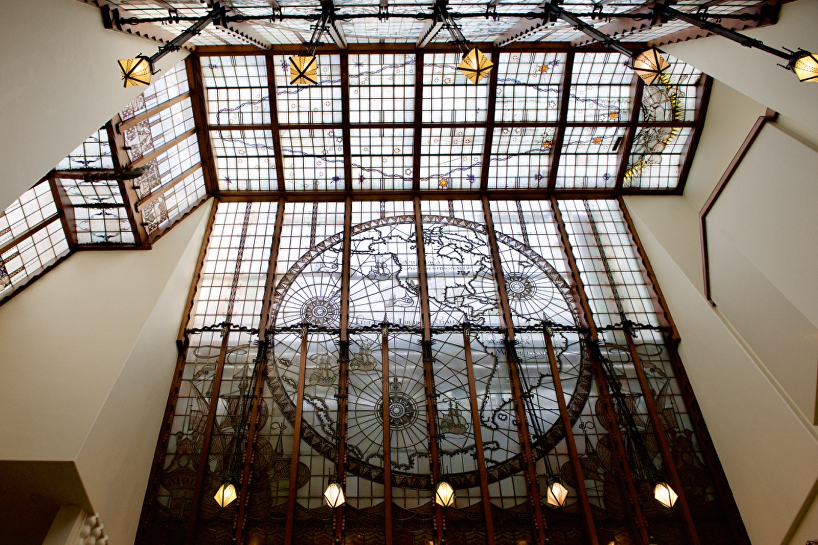 Glas-in-loodplafond met wereldkaart en maritieme motieven in Grand Hotel Amrâth Amsterdam, gezien vanaf de binnenzijde van het atrium.