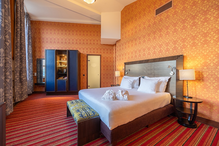 Junior Suite in Grand Hotel Amrâth Amsterdam with king-size bed, colorful interior, and coffee and tea facilities.