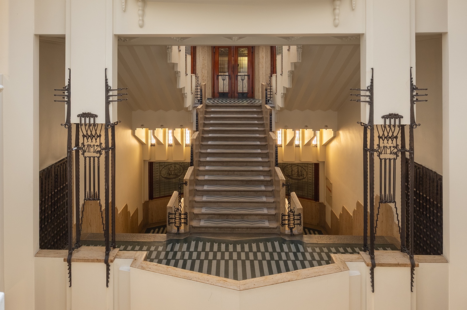 Monumentaal trappenhuis in Grand Hotel Amrâth Amsterdam met art-deco details, smeedijzeren ornamenten en glas-in-lood dakramen. Een fotogenieke fotoshoot locatie in Amsterdam.
