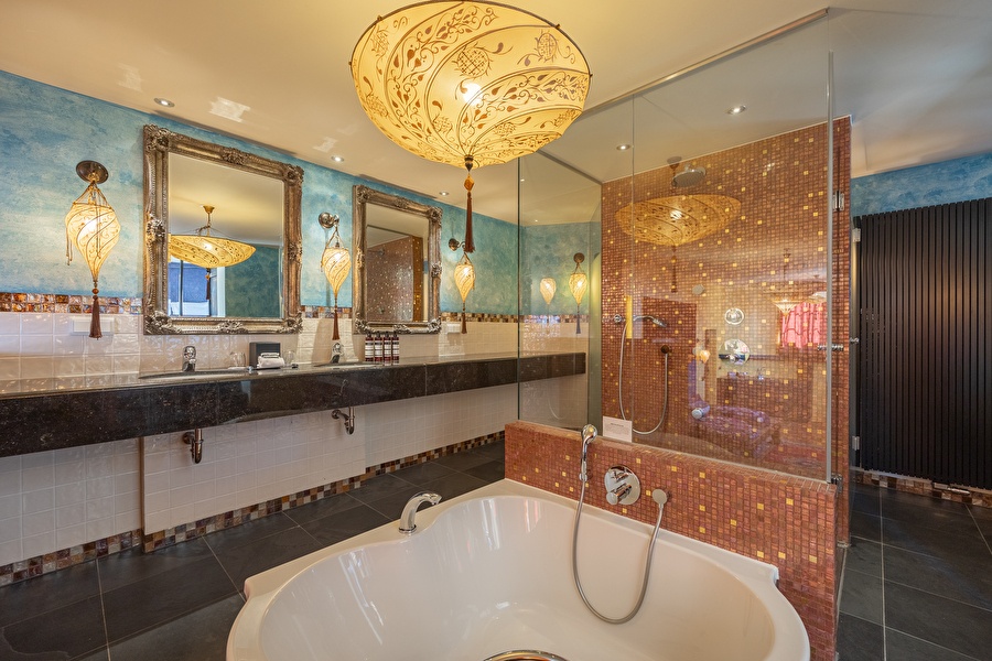 Luxury bathroom of the Oriental Suite with mosaic shower, freestanding bath, and decorative lamps in oriental style.