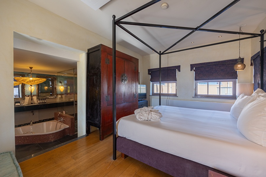 Eastern Suite with canopy bed, Asian-inspired interior, and open bathroom with freestanding bath.