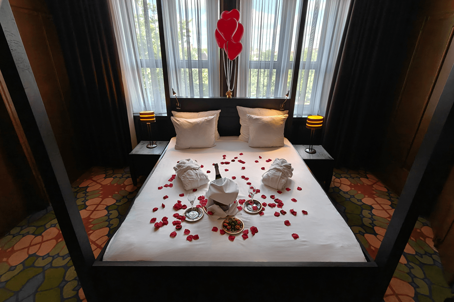Romantic scene with champagne and rose petals on the bed and roses in the corner