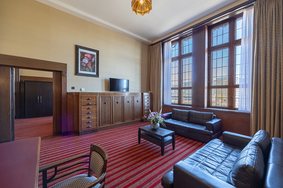 Seating area of the Suite with leather sofas, flowers on the table, and a view of the Oosterdok.
