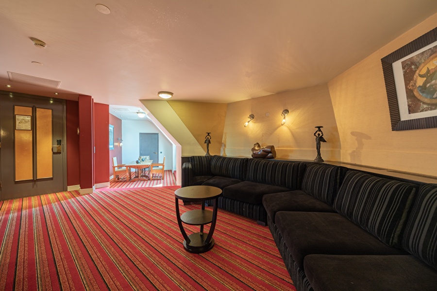 Royal seating area in the Tower Suite with long black sofa, art objects, and Art Nouveau details.